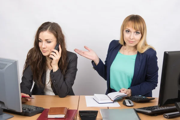 A garota no escritório confusa indica colega falando ao telefone — Fotografia de Stock