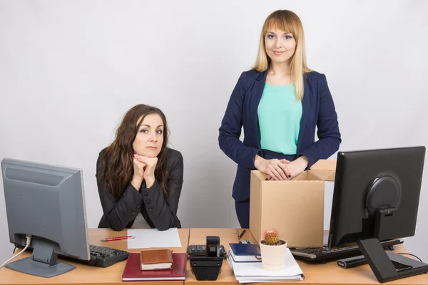 The girl in the office is facing the box with things near the colleague sitting next — Stock Photo, Image