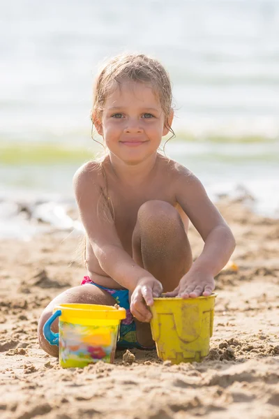 Ребенок играл на песчаном пляже с прудом и лепниной из песка — стоковое фото