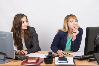 Office worker looking with distaste at the colleague sitting next to staring at a computer monitor clipart