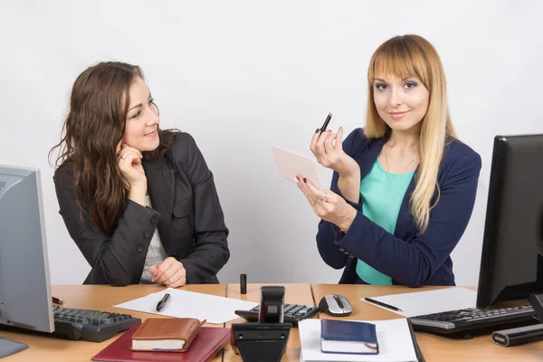 Empleado de oficina en su escritorio mirando a su colega, que tiene lápiz labial y espejo en la mano — Foto de Stock