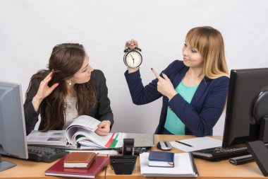 Girl shows a colleague in the office the rest of the working time on the clock clipart