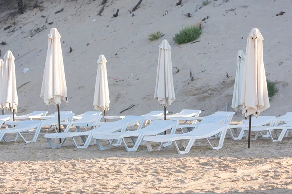 Reihen leerer Liegestühle am Strand mit aufgeblasenen Sonnenschirmen — Stockfoto