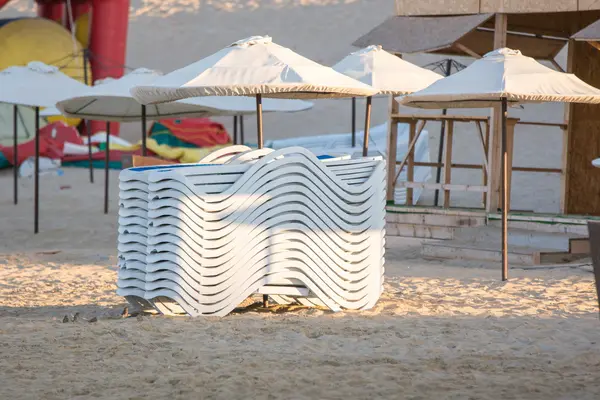 Gestapelte Stühle am Abend am Strand unter den Sonnenschirmen — Stockfoto