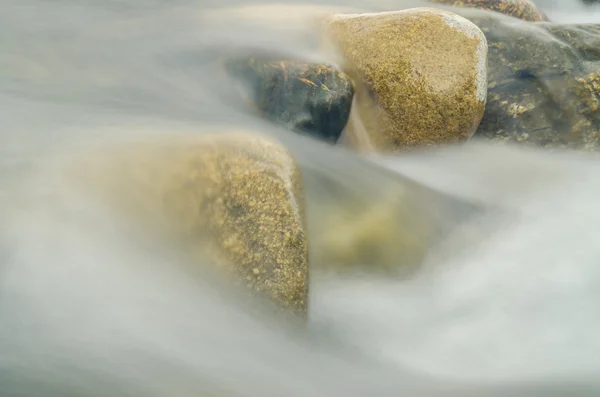 Corriente entre las piedras del río, borrosa por una velocidad de obturación lenta —  Fotos de Stock