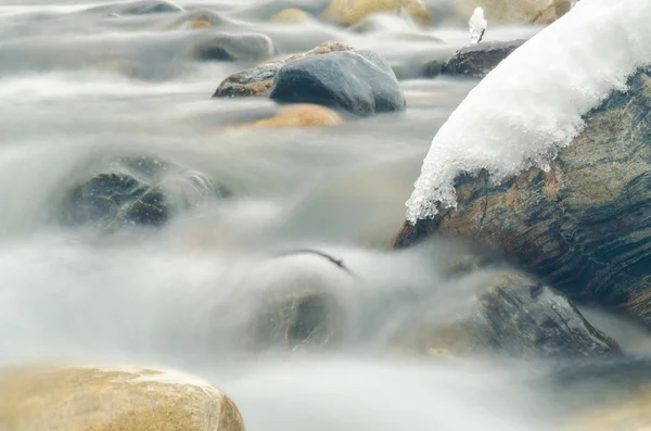 Close-up da corrente entre as pedras de um riacho de montanha, fotografado com uma longa exposição — Fotografia de Stock