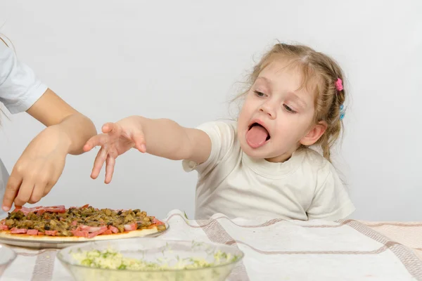 Menina com a língua estendendo uma mão para puxar a pizza, que prepara sua irmã mais velha — Fotografia de Stock