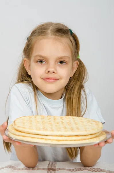 Flickan med en liten leende håller en pizza skorpa på en tallrik — Stockfoto