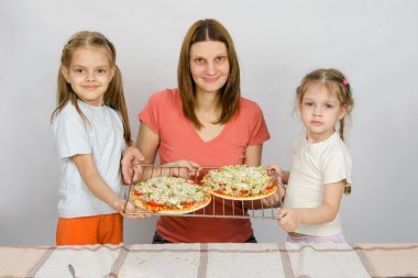 Anne ve iki küçük kızı iki henüz bir fırın tepsisine pişmiş pizza yapmamıştı göstermek