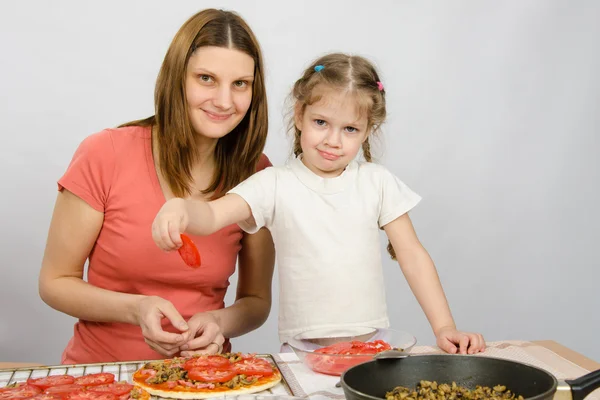 Küçük beş yıllık kız pizza malzemeleri üzerinde anne yayılmasına yardımcı olur — Stok fotoğraf