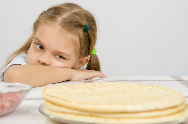 Flickan vid köksbordet lade huvudet på handen, och med en aptit för att titta på kakor framför henne — Stockfoto
