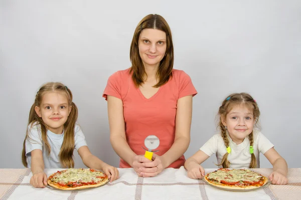 Pizza ve iki kime iki kızı için bir bıçakla annem masada oturdu pizza — Stok fotoğraf