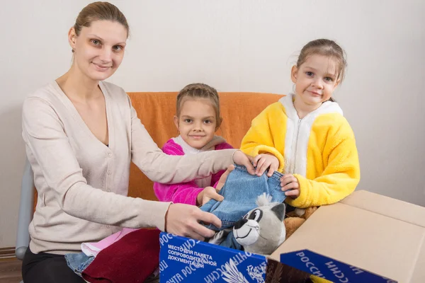 Volgogrado, Rusia - 24 de febrero de 2016: Madre y dos hijas en el marco miraron recoger el paquete para ser enviado por correo Rusia — Foto de Stock