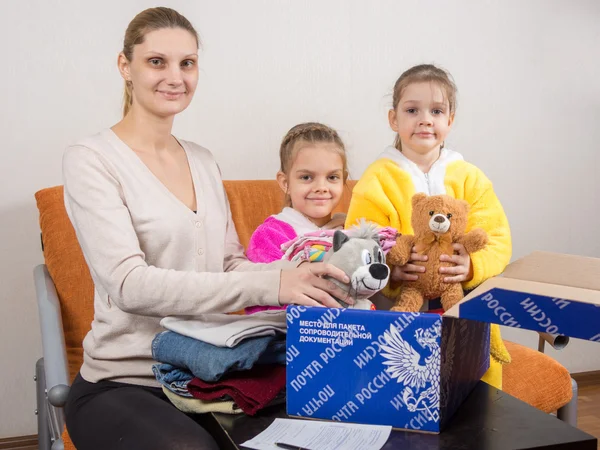 Volgograd, Rússia - 24 de fevereiro de 2016: Mãe e duas filhas colocam brinquedos em sua caixa original correio Rússia — Fotografia de Stock