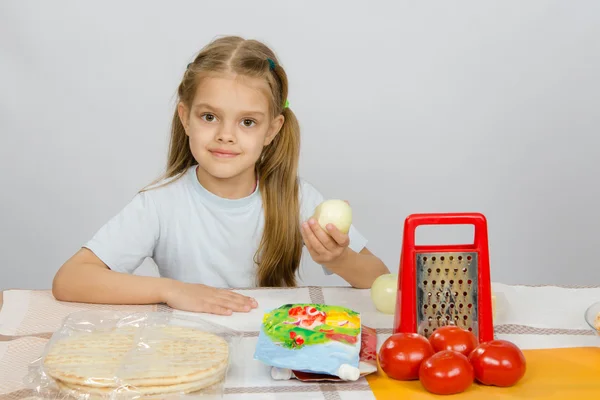 Niña de seis años sentada en la mesa de la cocina frente a ella son verduras, base y otros ingredientes para la pizza — Foto de Stock