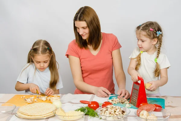 Mum with a five-year daughter watched as the eldest daughter cutting mushrooms pizza — Stock Photo, Image