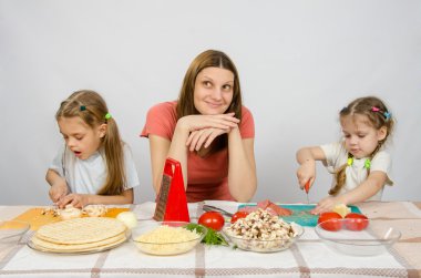 Anne Mutfak masasında iki küçük kız yakın konsantrasyon kesme ürünleri rüya gibi bir görünüm ile oturuyor.