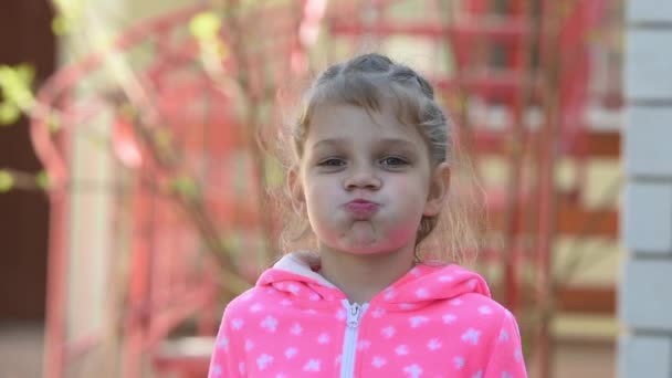 Flicka fem år gammal rolig blåses upp kinderna — Stockvideo