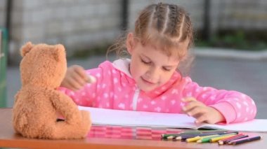 Beş yaşındaki bir kızın düzgünce boyalı silgi kalem albümünde siler