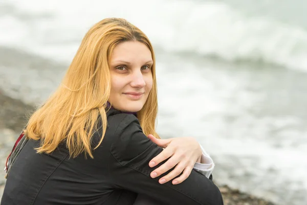 Portrait de assis sur la plage mystérieusement fille souriante par temps nuageux — Photo