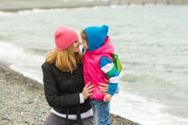 Küçük kız ve annesi burun soğuk havalarda sahilde dokunmadan