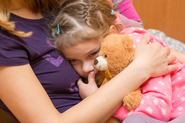 Meisje met een teddybeer klampte zich vast aan haar moeder met een droevige uitdrukking op zijn gezicht — Stockfoto