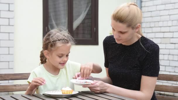 Mamma e figlia sette anni nel cortile seduto al tavolo sypyat posypku su Easter cupcake — Video Stock