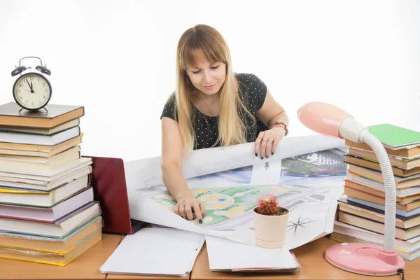 Girl student studying design drawing master plan at a table cluttered with books — Stock Photo, Image