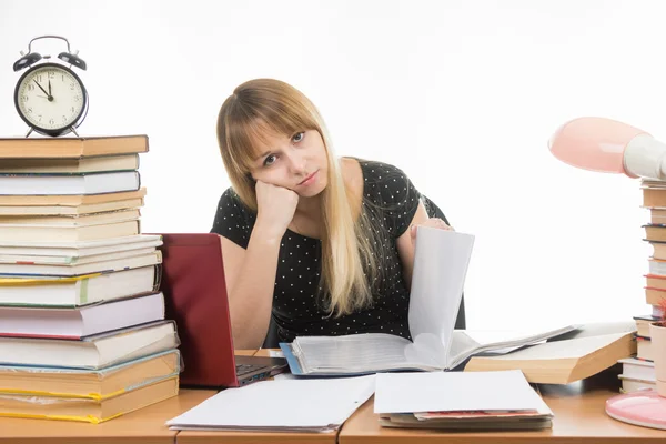 Papier étudiant feuilles ternes à une table parmi les livres et les piles de regards dans l'image Photo De Stock