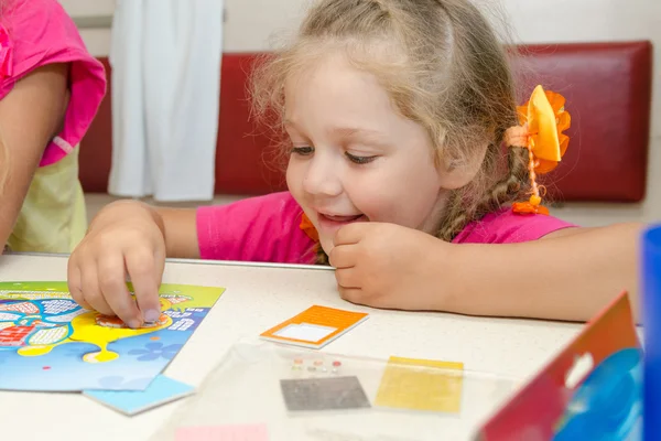 Fyraårig flicka på ett tåg som sitter vid bordet på lägre klassens plats bil och entusiastiskt spelar — Stockfoto