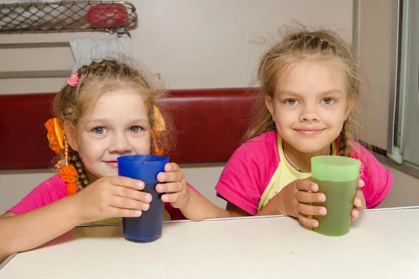 Duas meninas irmãs no trem sentadas na mesa no lugar mais baixo no vagão do compartimento de segunda classe com óculos na mão — Fotografia de Stock