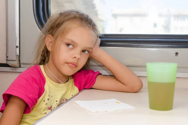 Menina de seis anos pensativa e cansada sentada no trem na mesa no compartimento de segunda classe — Fotografia de Stock