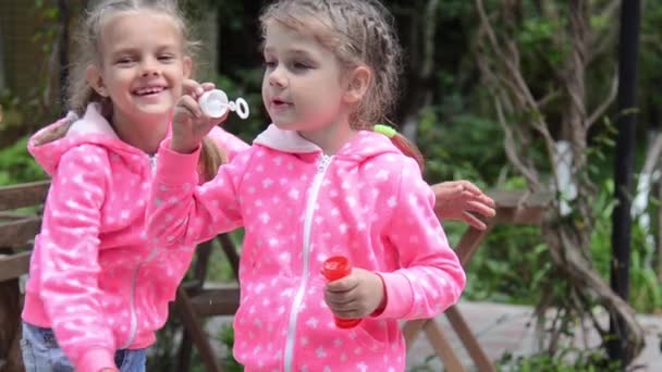Dívka foukat bubliny, náhle objala druhou holku, a společně pokračovali k ráně bubliny — Stock video