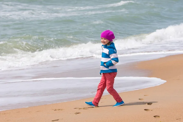 Счастливая девушка, идущая вдоль берегового морского пляжа в теплый весенний день — стоковое фото