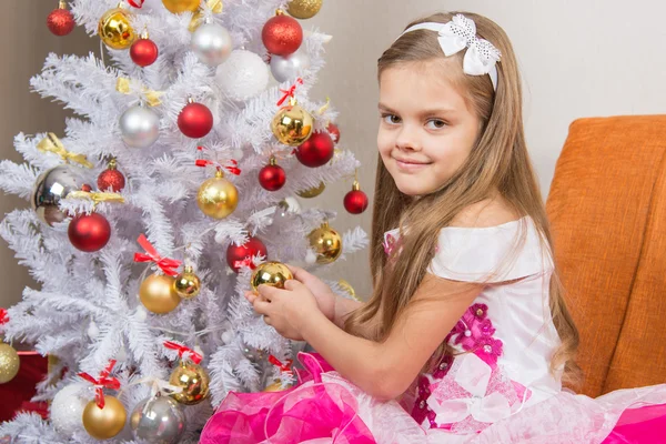 Siete años chica en un hermoso vestido trata juguetes de Navidad y miró en el marco — Foto de Stock