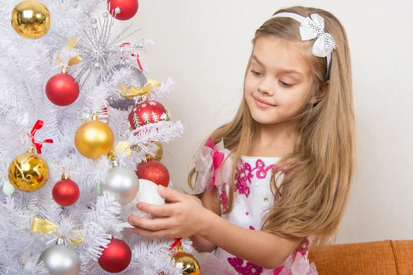 Siete años chica en un hermoso vestido trata juguetes de Navidad —  Fotos de Stock