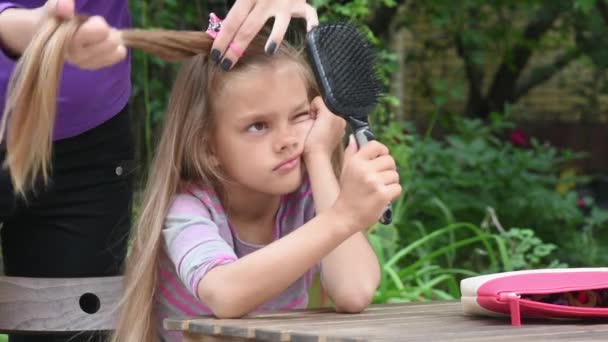 Fille ennuyé jusqu'à ce que ma mère tresse ses cheveux longs et en regardant le reflet dans le miroir — Video