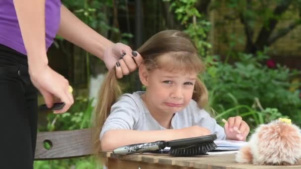 Мать расчесывает дочь с длинными волосами, что очень болезненно — стоковое видео