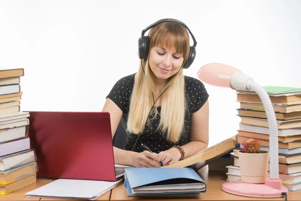 Student luisteren naar muziek op hoofdtelefoons die zich bezighouden met de voorbereiding voor het examen — Stockfoto