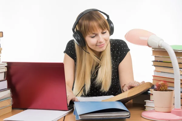 Happy student sedí u stolu a příprava na zkoušky v sluchátka — Stock fotografie