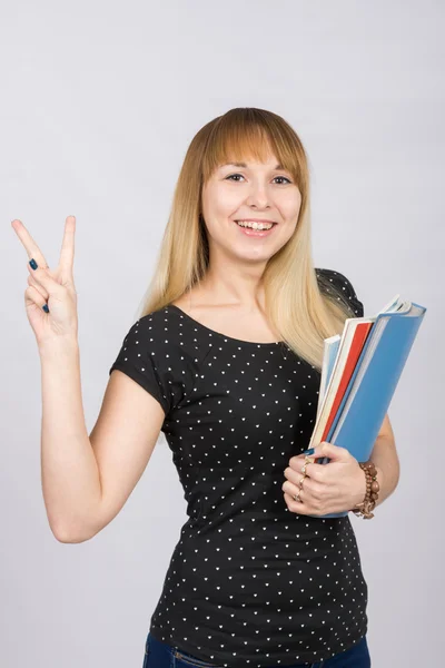 La chica alegre con una carpeta en sus manos muestra gesto "Victoria" mano de la victoria — Foto de Stock