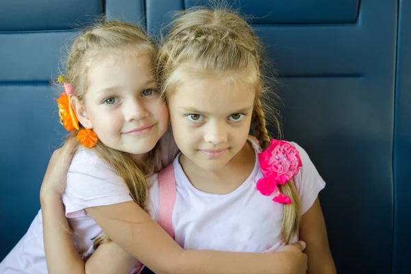 Duas meninas abraçando olhar na moldura, sentado em um trem elétrico, close-up — Fotografia de Stock