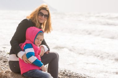 Annem ve beş yaşındaki kızı plajda oturmak ve çerçeve dönüm baktı