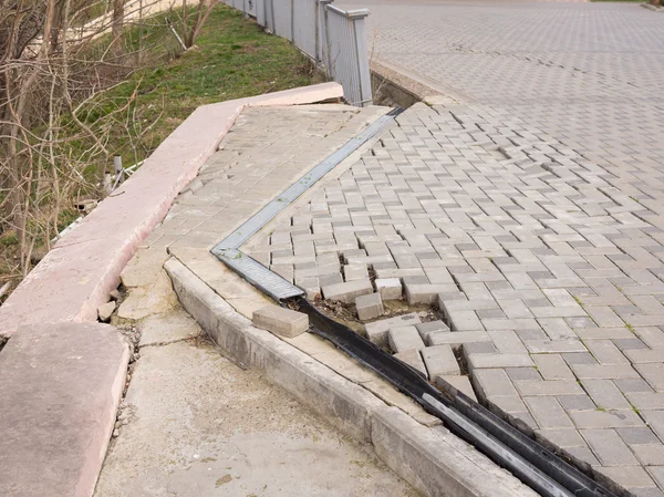 The destruction of the pedestrian walkway of pavers fixed concrete screed, as well as the breaking behavior of the fence — Stock Photo, Image