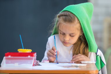 Biraz darmadağınık kız suluboya bahçedeki masada oturma boyalar