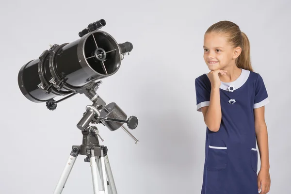 Chica de siete años con interés mirando un telescopio reflector — Foto de Stock