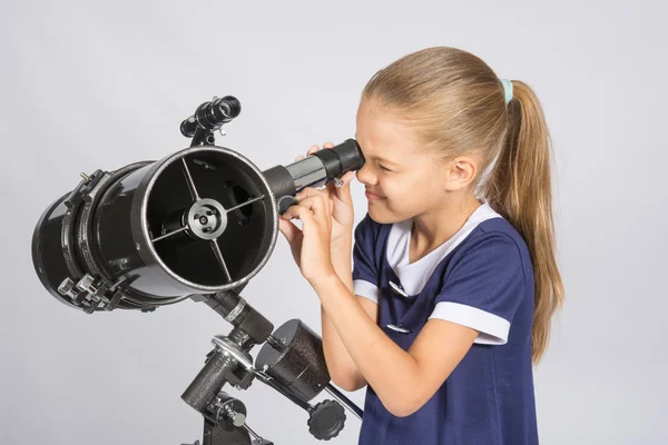 Sjuåriga flickan vindögd med intresse ser i en reflektor teleskop — Stockfoto