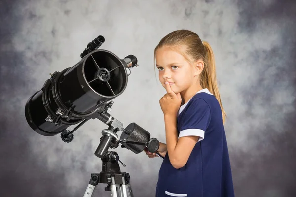 Niña de siete años mira al cielo mientras está de pie en el telescopio — Foto de Stock