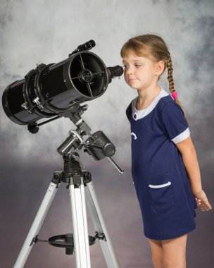 Girl lover of astronomy with interest looks in the eyepiece of the telescope clipart