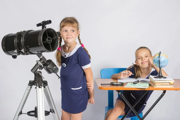 Meisje astronoom kijkt naar de hemel, het andere meisje dat gelukkig zit aan de tafel — Stockfoto